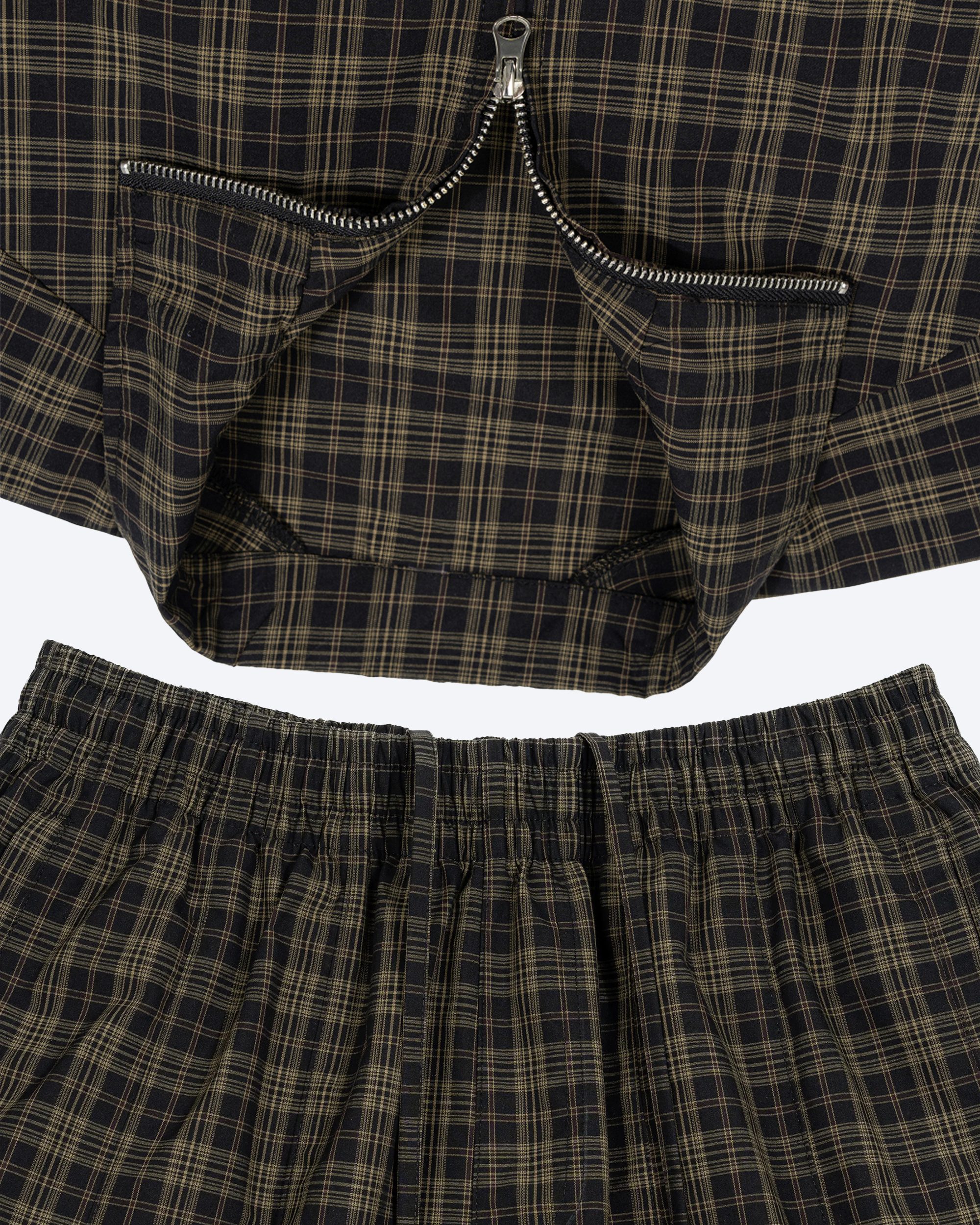 Olive plaid wide-leg shorts from ODMPOD displayed on a hanger, showing the relaxed fit and stylish pattern.