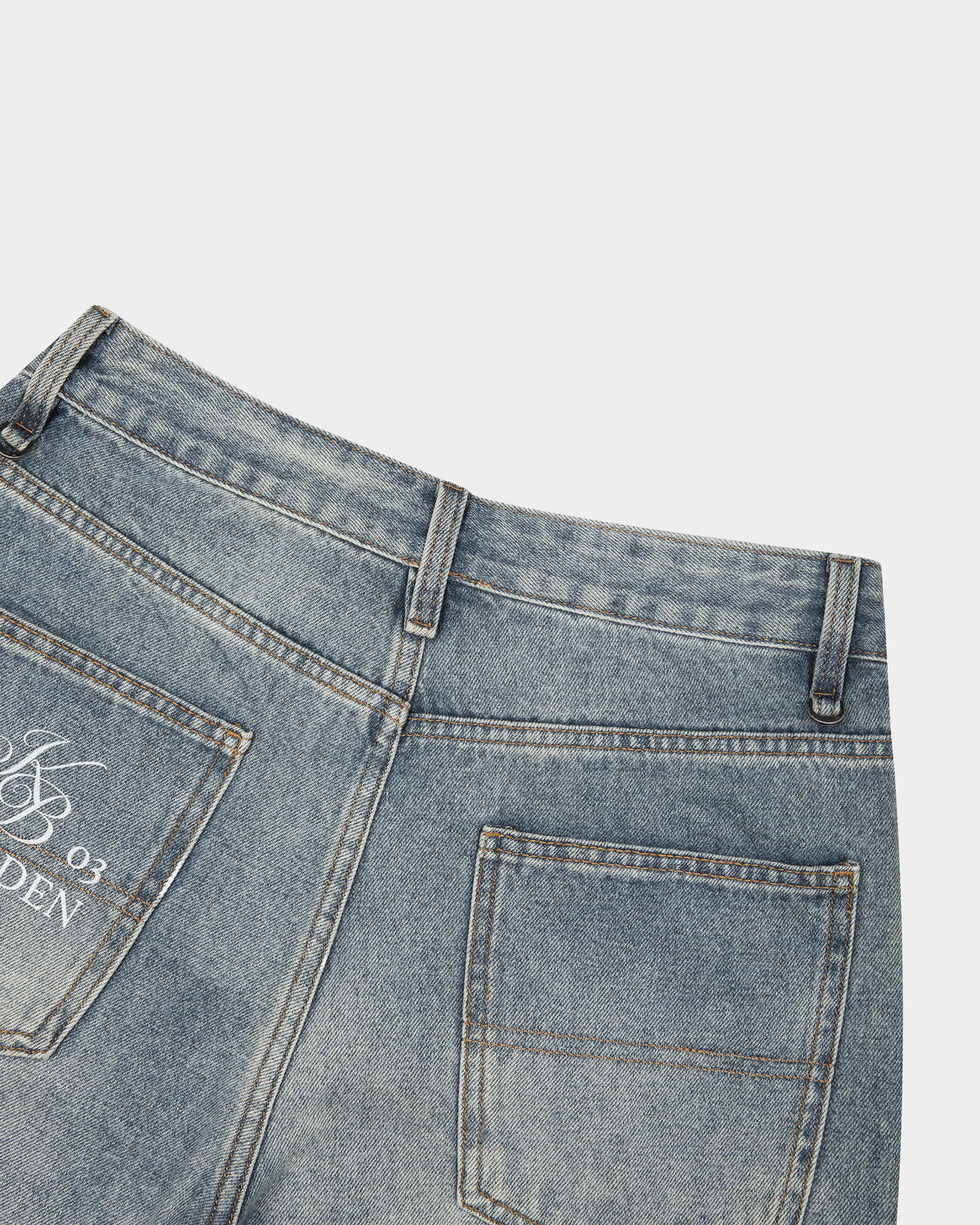 Faded blue denim shorts by ODMPOD with distressed details and rolled cuffs on a plain white background.