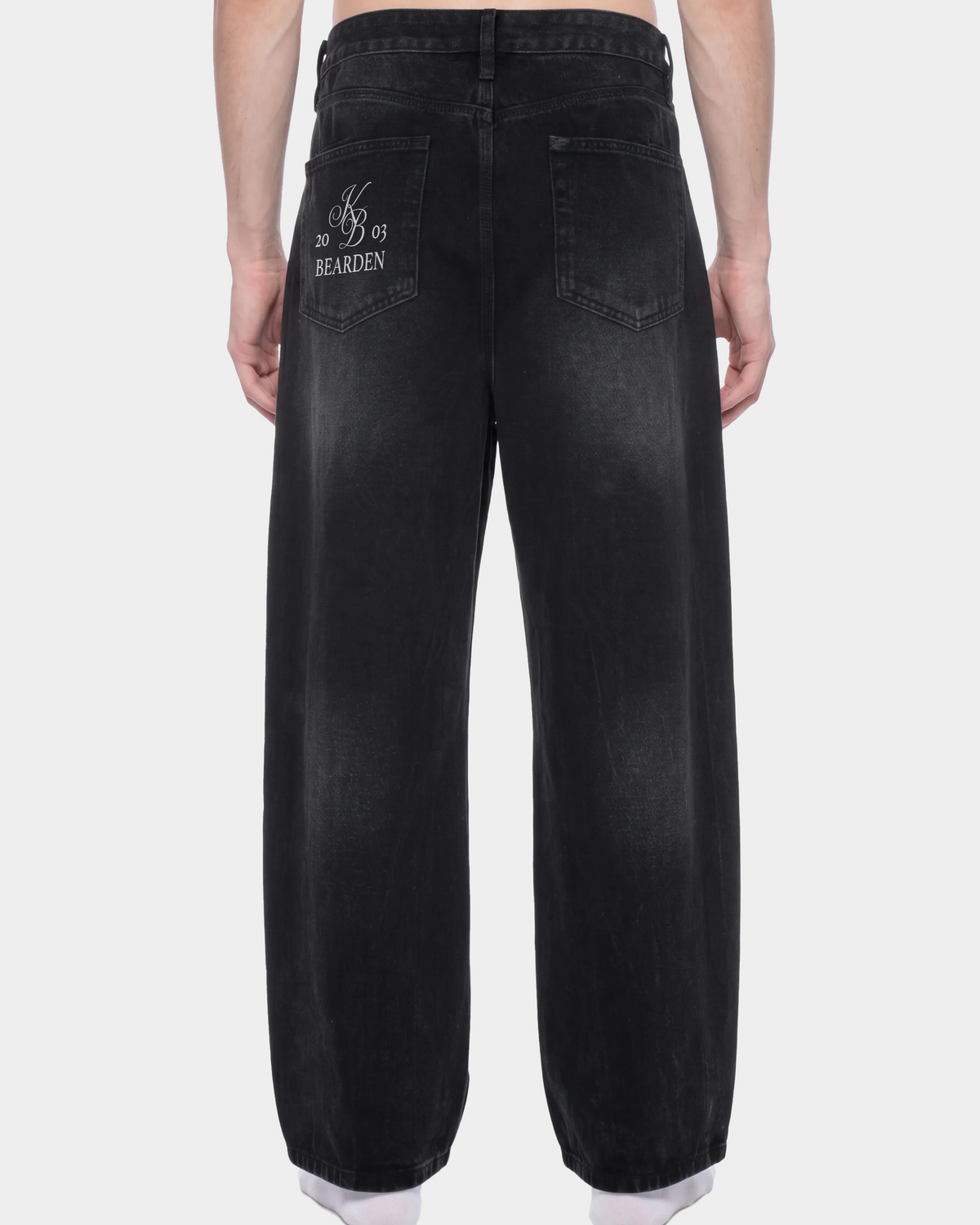 Faded black wide-leg jeans by ODMPOD with relaxed fit and high-rise waist, shown on a model against a neutral background.