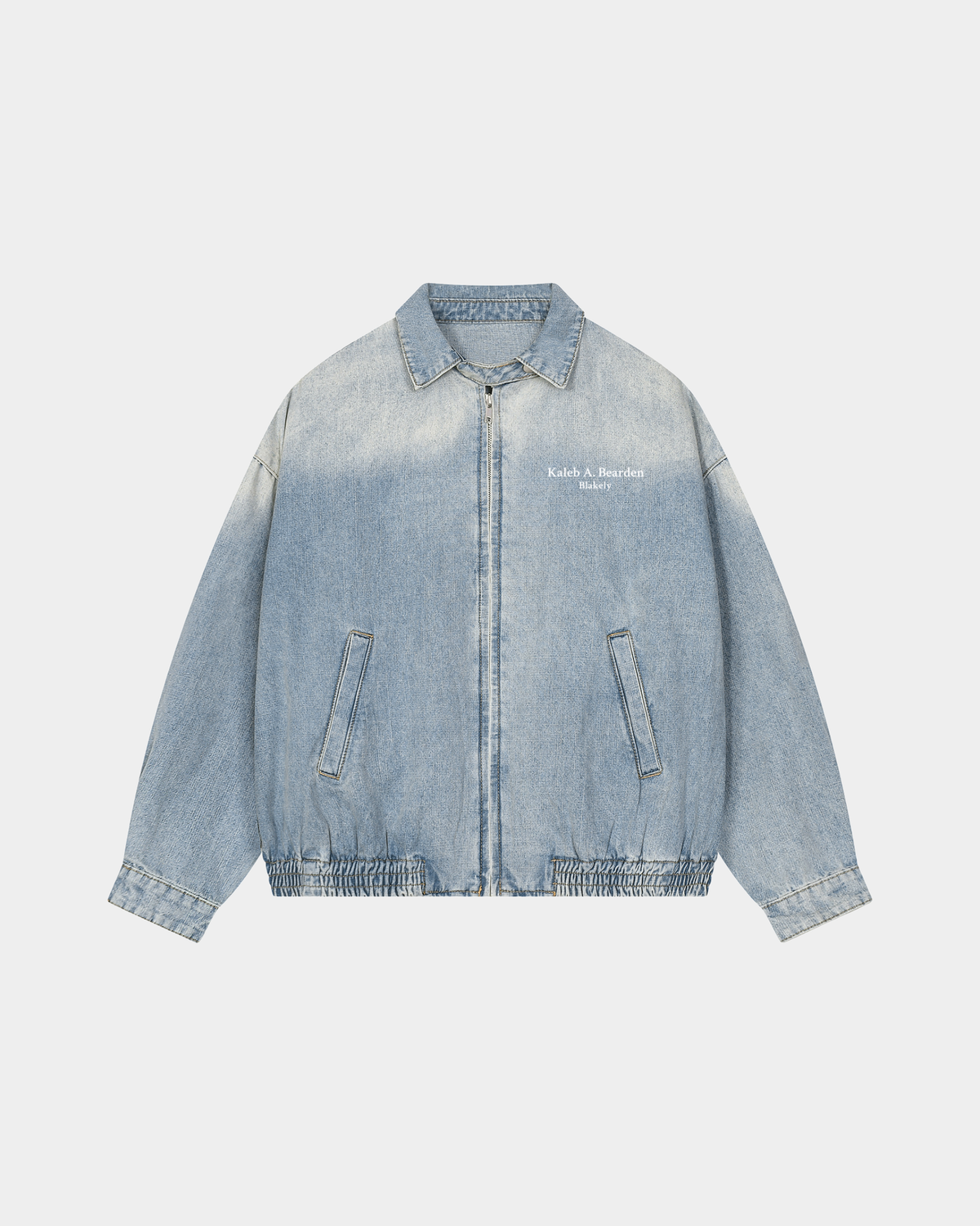 ODMPOD KAB Washed Blouson in denim with button-up front and ribbed cuffs, shown hanging on a hanger for a casual stylish look.