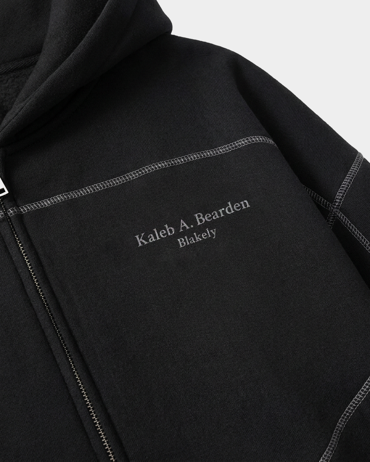 ODMPOD Origin Monogram Contrast Hoodie showing detailed contrast stitching and monogram logo on the front and sleeves.