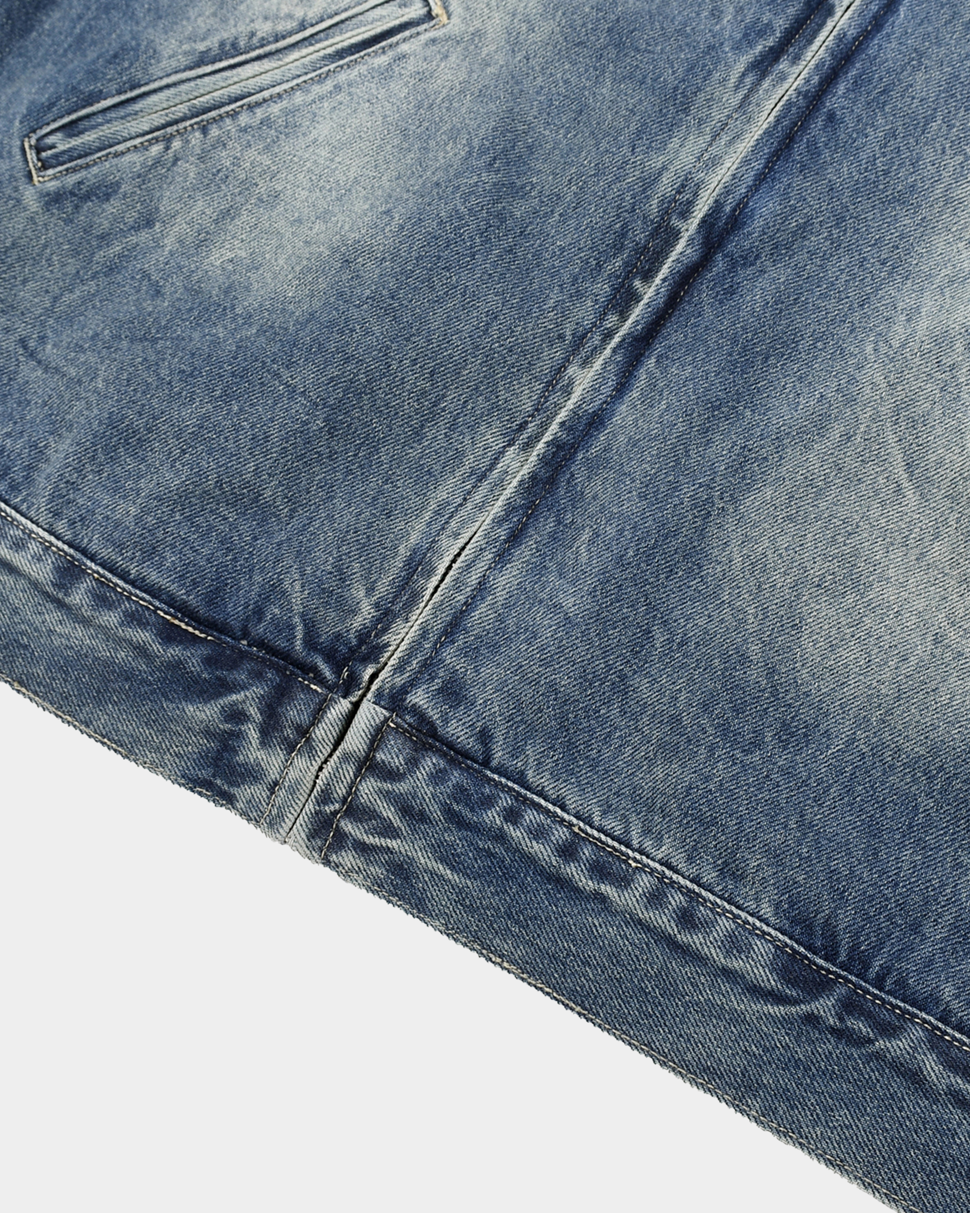 Washed denim jacket by Kaleb A. Bearden hanging on a hanger, showcasing its classic blue color and casual style.
